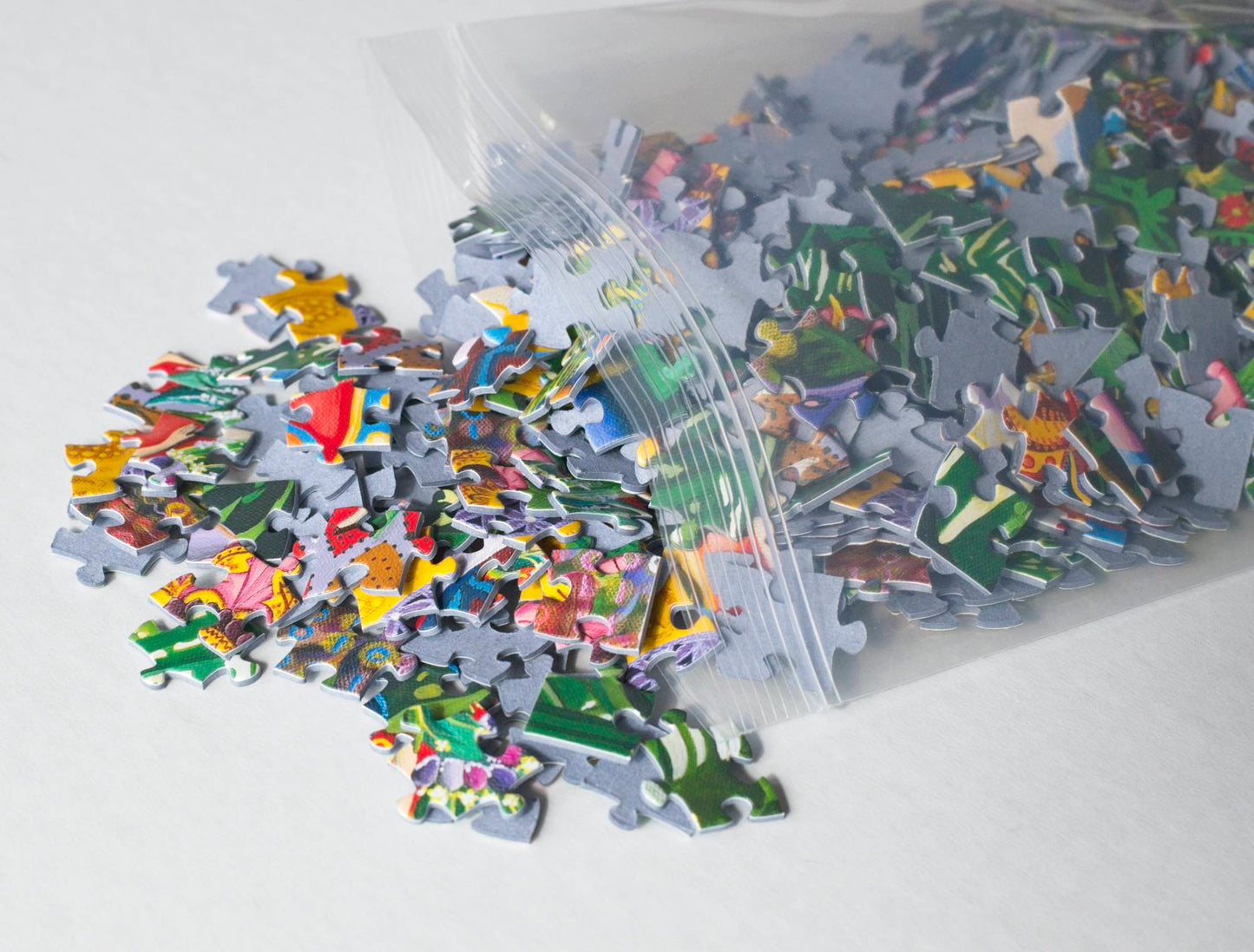 A resealable bag spilling out colorful jigsaw puzzle pieces