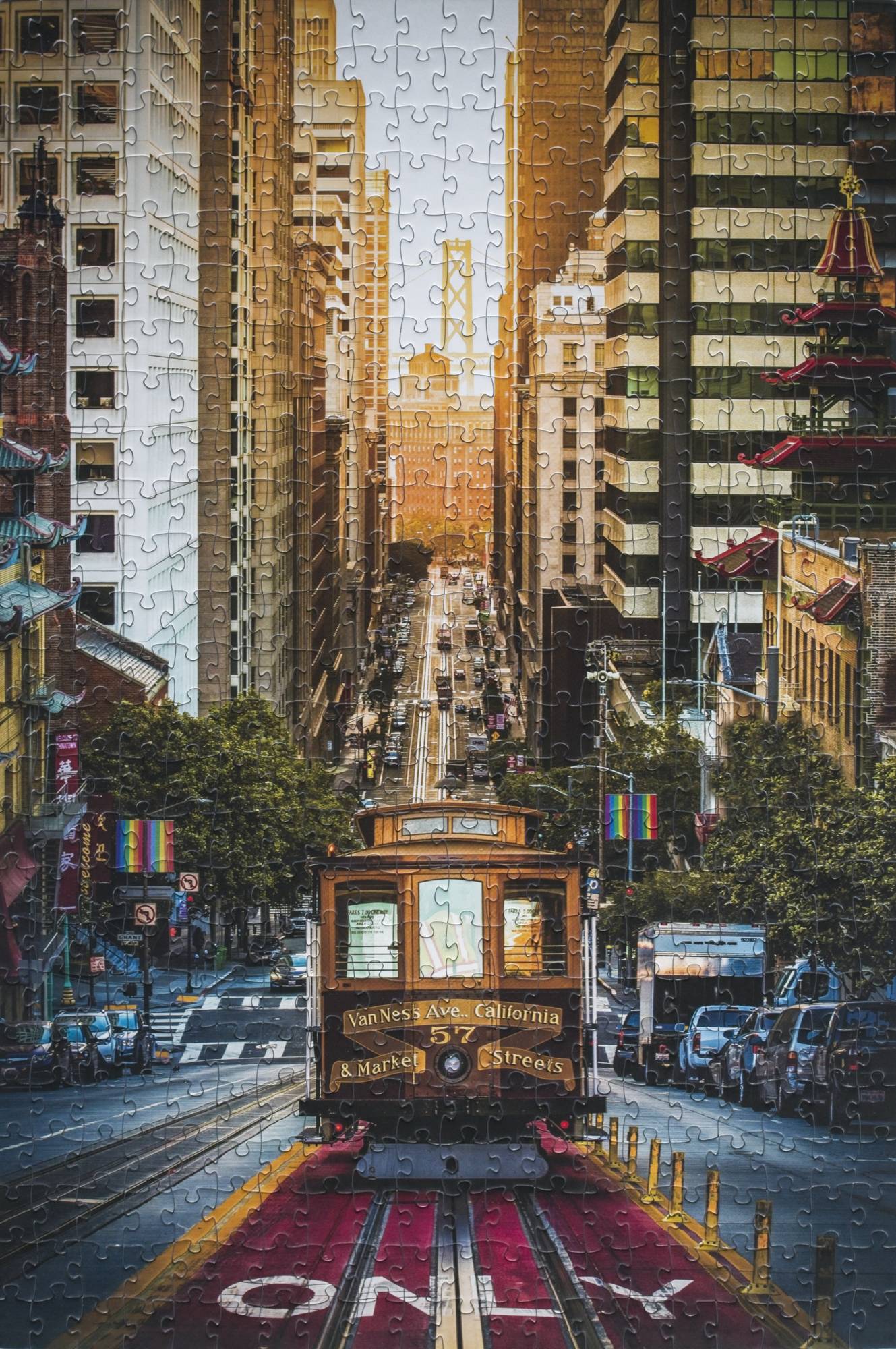 A completed jigsaw puzzle of a photograph of a trolley coming up a San Francisco hill toward the viewer with the sunrise and a bridge in the background