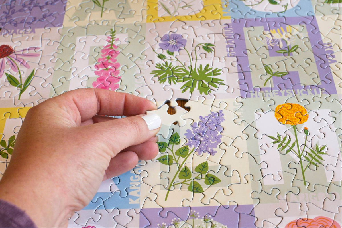 A hand holding an irregularly shaped puzzle piece hovering near the empty space on an otherwise complete section of the puzzle.
