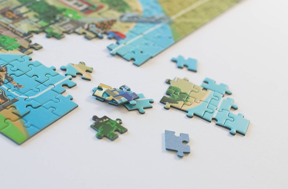 A close-up of several loose puzzle pieces and a section with a completed section in the background on a white surface.