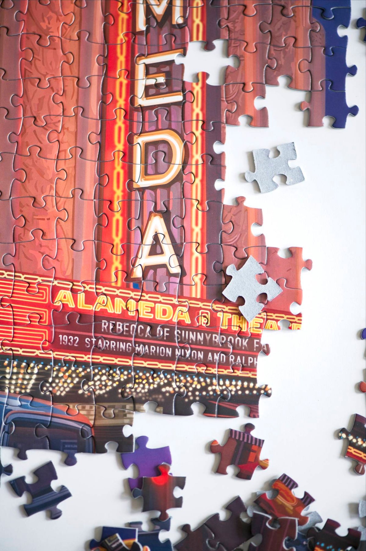 A close-up photo showing the marquee section of the partially assembled jigsaw puzzle with some scattered pieces around and some turned over showing blue board.