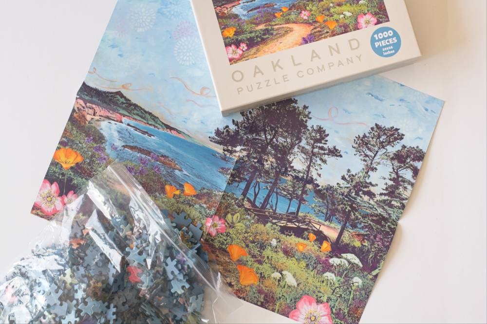 An unassembled 1000-piece jigsaw puzzle from Oakland Puzzle Company, shown with its box and a clear plastic bag of loose puzzle pieces on a white background.