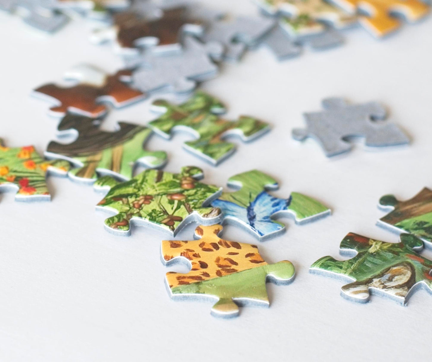 A close up photo of scattered colorful jigsaw puzzle pieces on blue board.