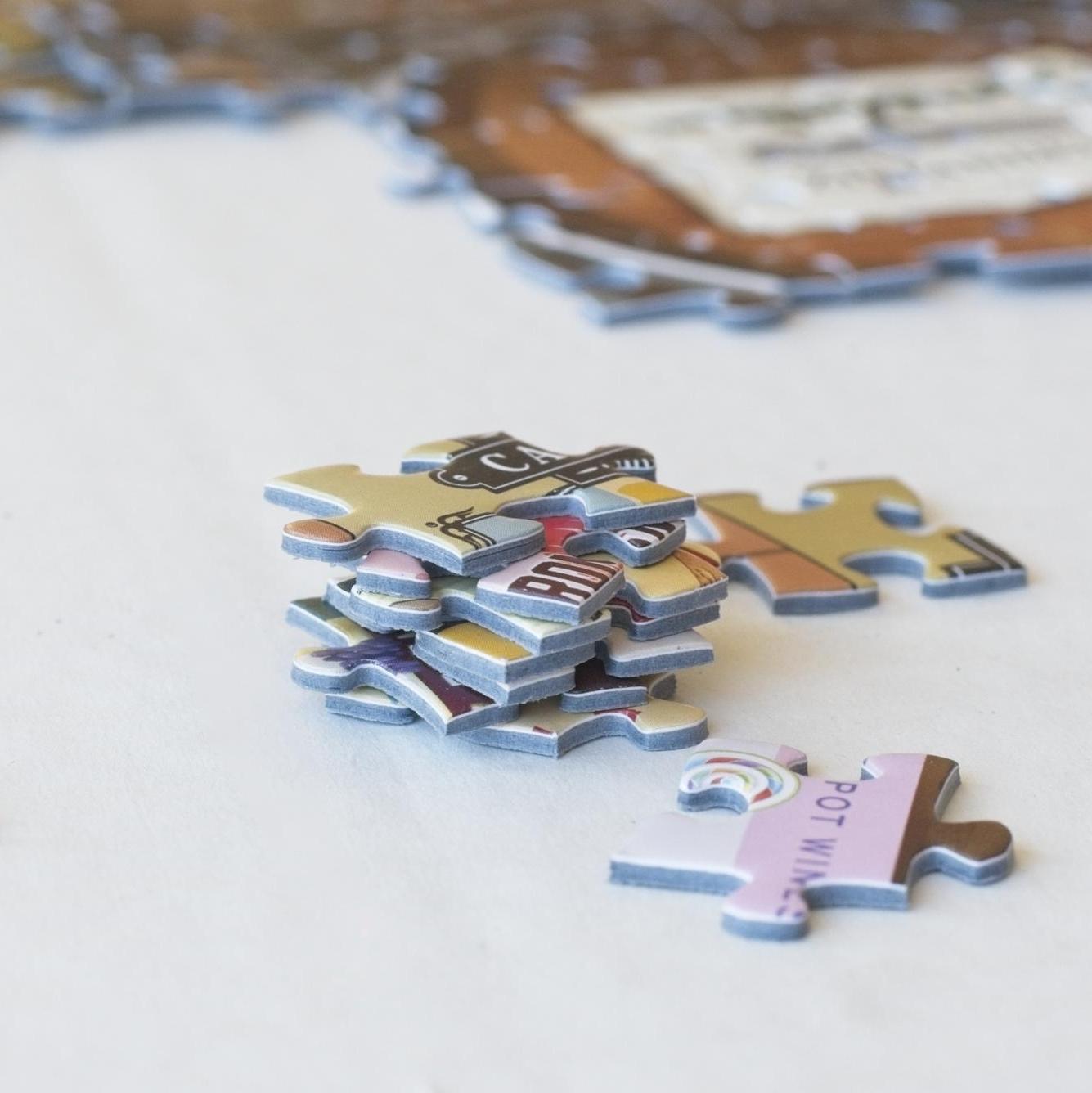  stack of colorful jigsaw puzzle pieces with a partially completed puzzle in the background
