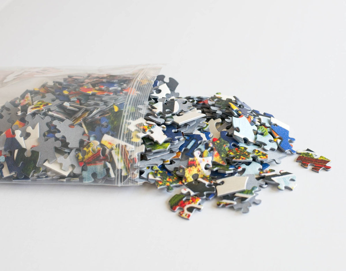 A resealable plastic bag spilling colorful puzzle pieces out onto a white surface.