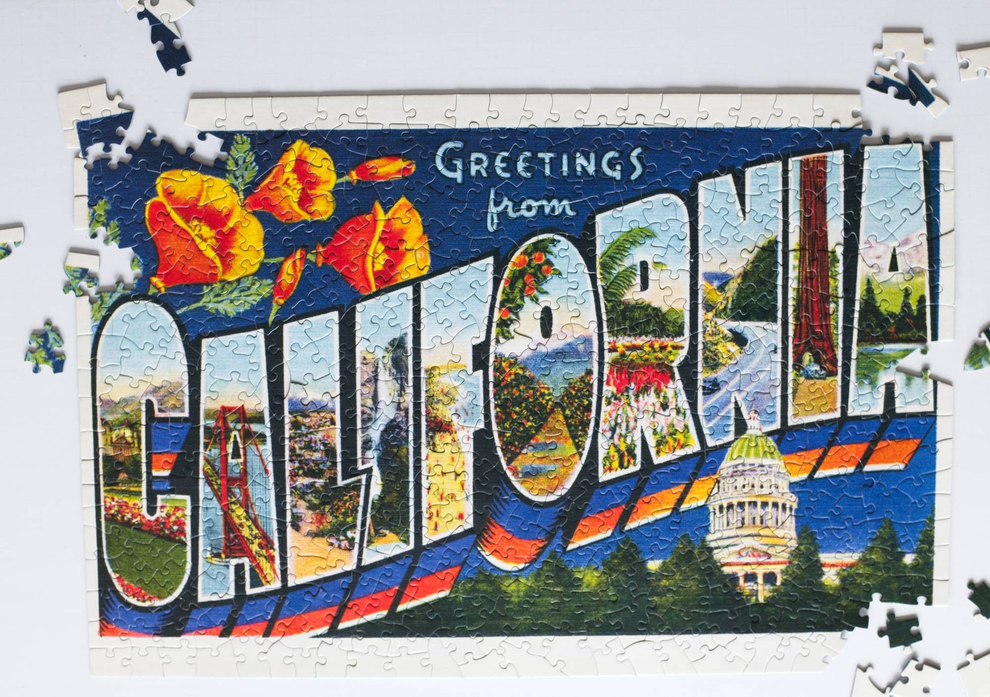 A partially completed puzzle featuring the image of a large letter vintage postcard with scenes from California