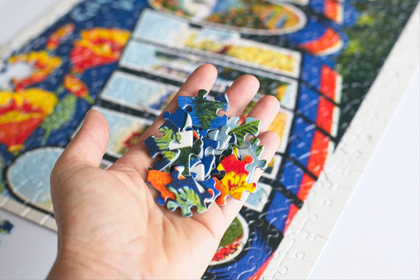A hand holding colorful puzzle pieces with a partially completed jigsaw puzzle in the background.