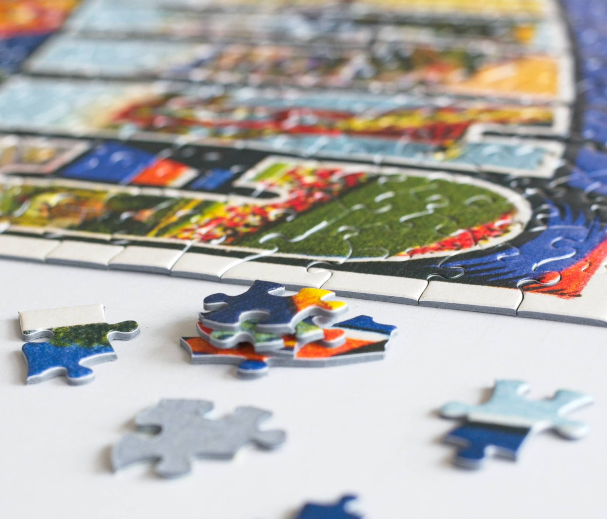 A stack and scattered colorful puzzle pieces next to a completed jigsaw puzzle