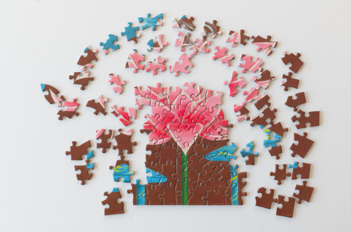 A photo of a partially completed pink lotus in a jigsaw puzzle. The remaining pink pieces are scattered above and around it. 