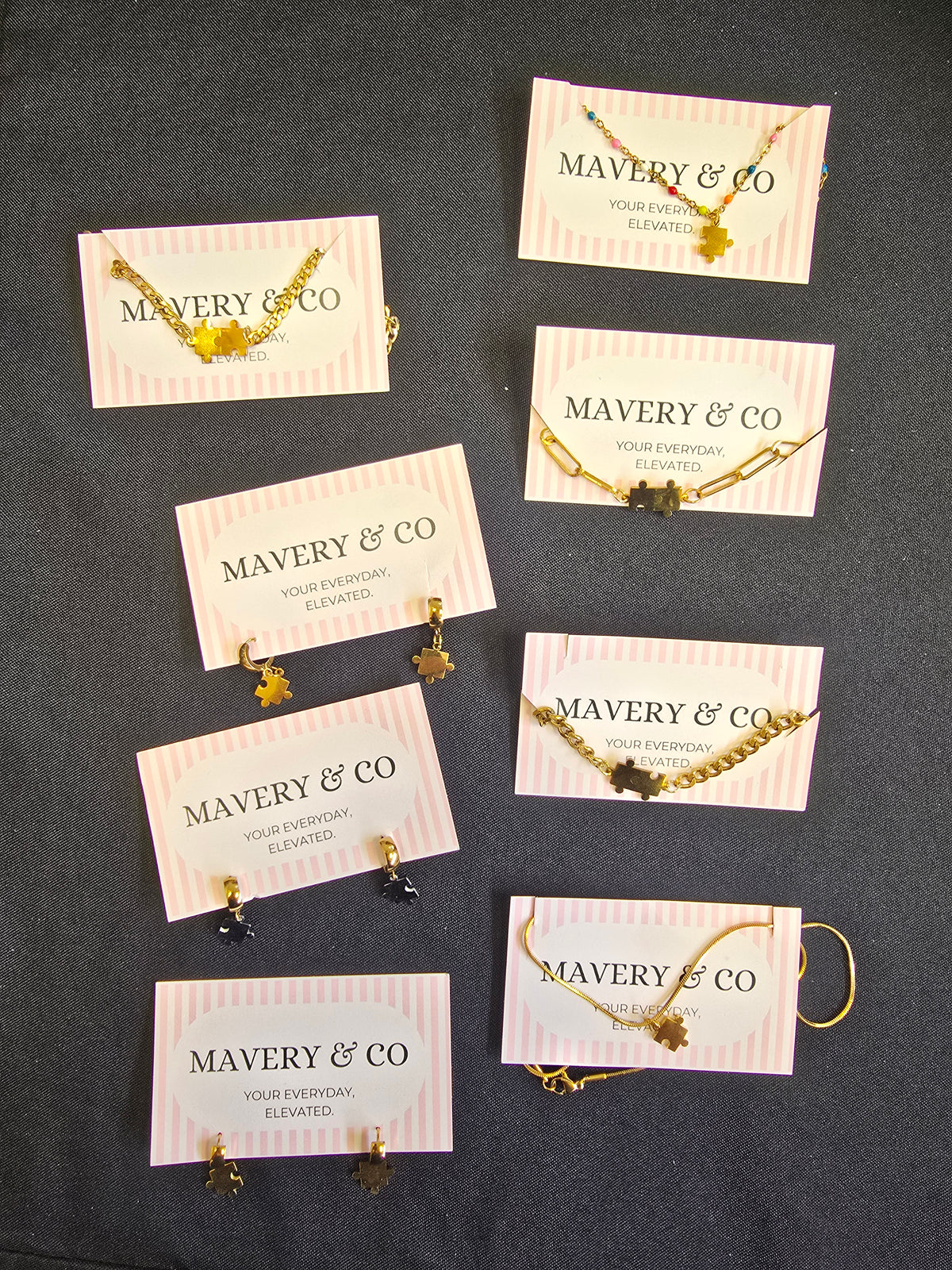Jewelry display with 'MAVERY & CO' on cards against a dark background