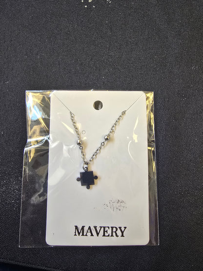 Silver beaded chain necklace with a puzzle piece pendant on a black background