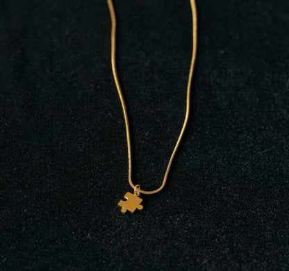 Gold snake chain necklace with a small pendant on a black background