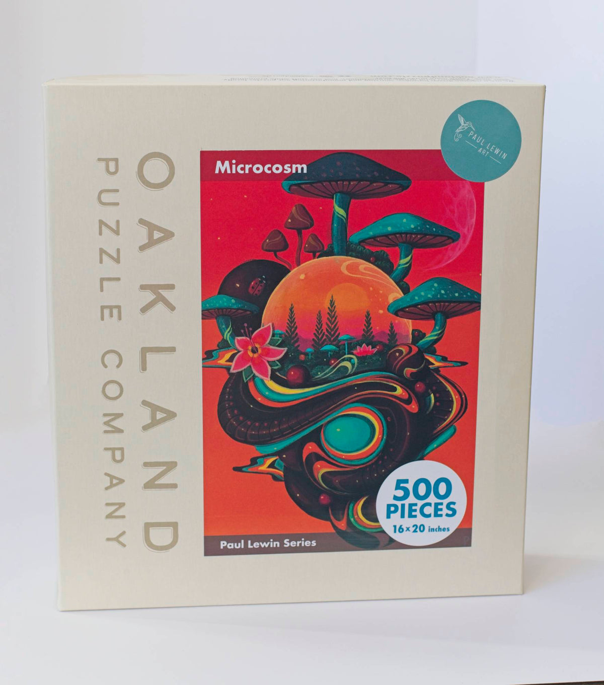 A box branded Oakland Puzzle Company with a colorful orange Afrofuturist image with mushrooms, flowers, and orbs titled Microcosm Paul Lewin Series