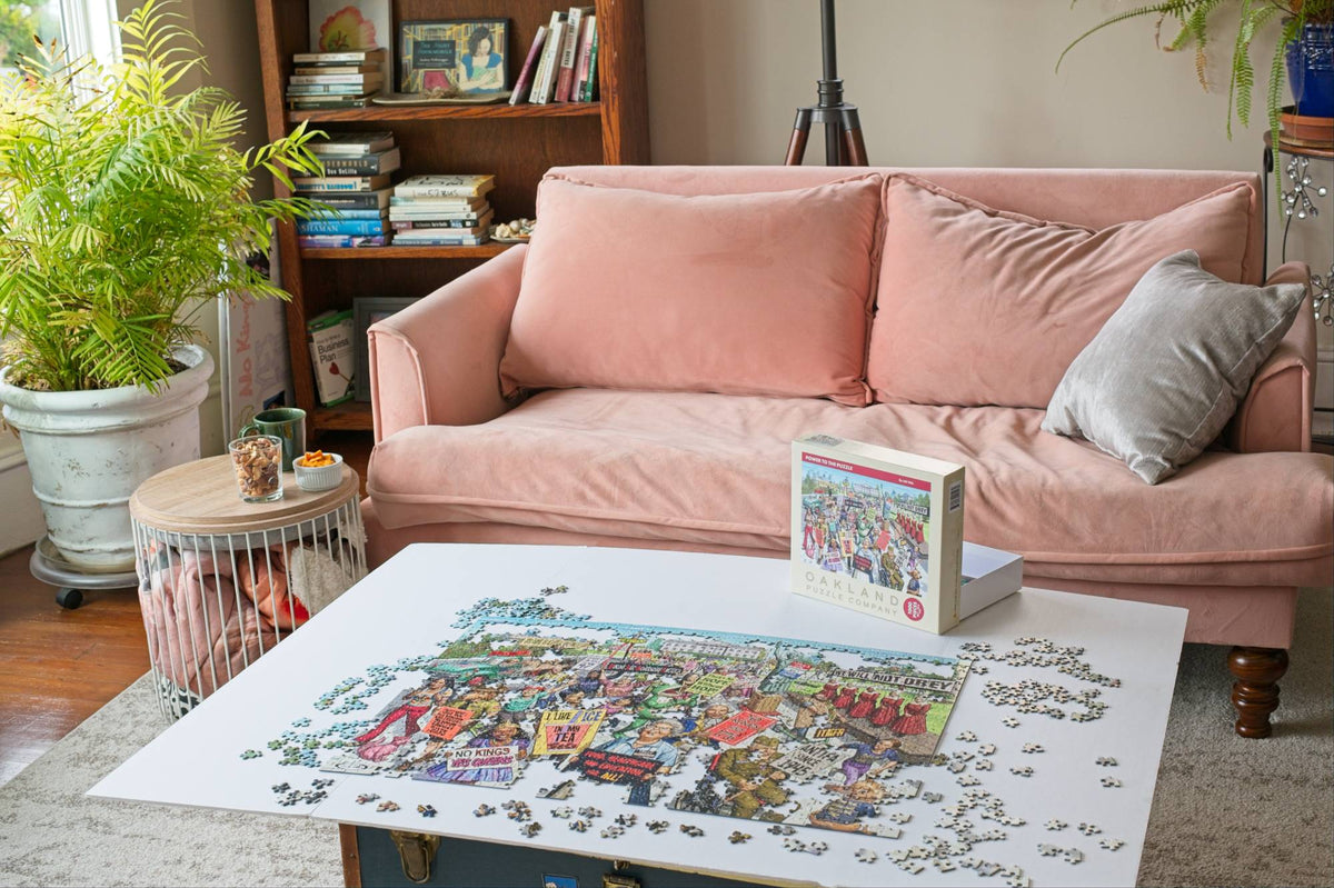 A welcoming bright living room with a partially completed jigsaw puzzle on a coffee table in front f a pink couch