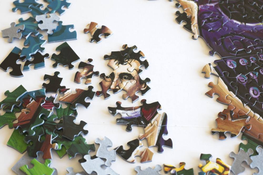 Jigsaw puzzle with a partially completed portrait and typewriter on a white background