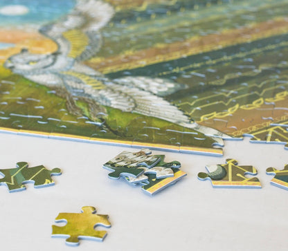 A stack of puzzle pieces with several scattered pieces with a partially completed puzzle in the background on a white surface