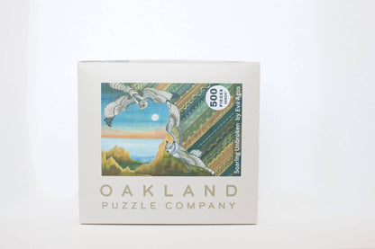 Oakland Puzzle Company puzzle box with artwork of birds and coastal landscape on a white background