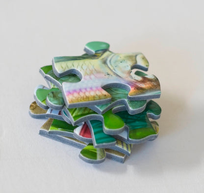 A close up of a  stack of colorful jigsaw puzzle pieces with a piece on top that looks like scales of a rainbow trout
